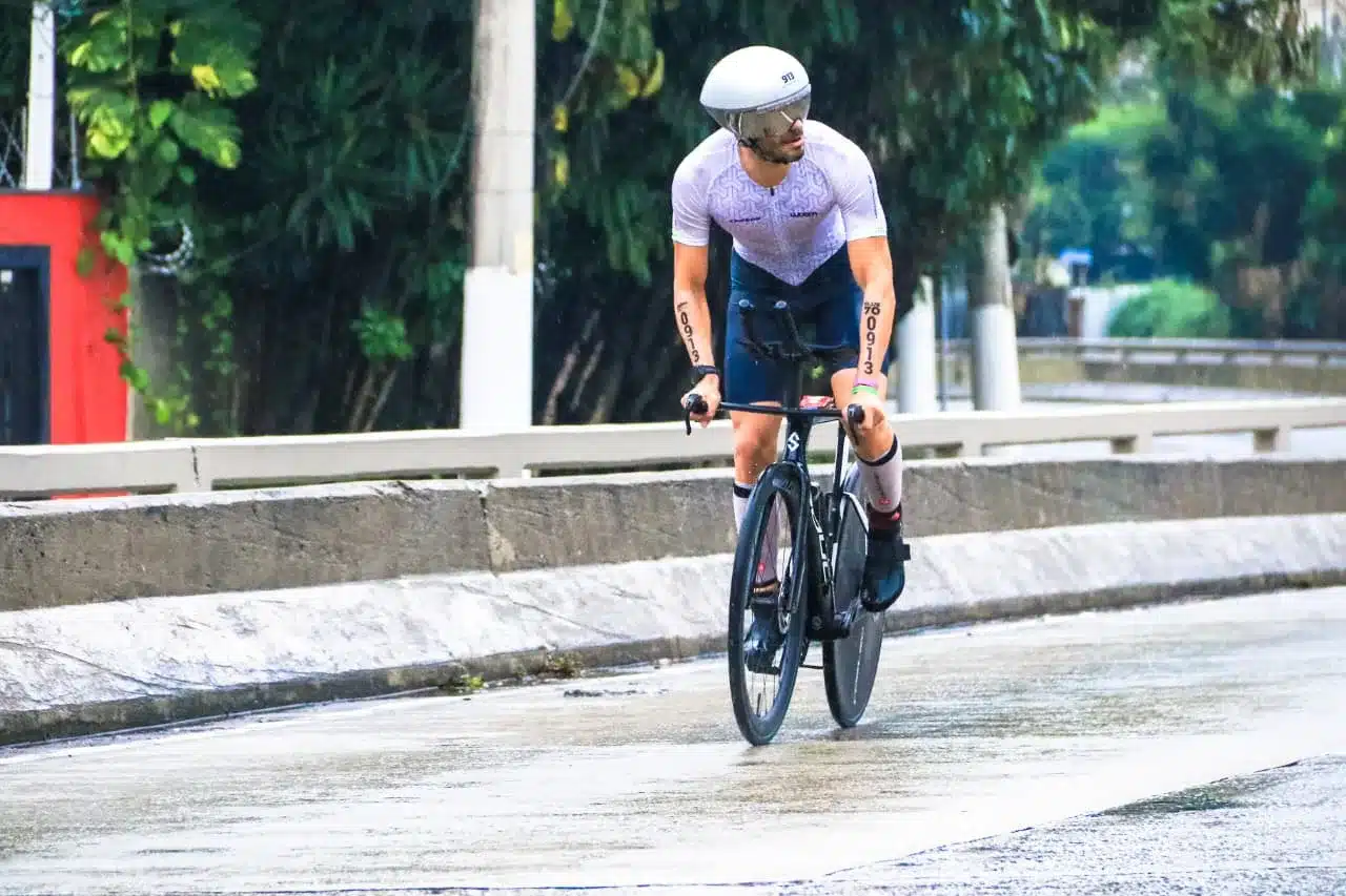 Marcos de Pauli pedalando no asfalto molhado durante o Ironman 70.3 São Paulo 2026